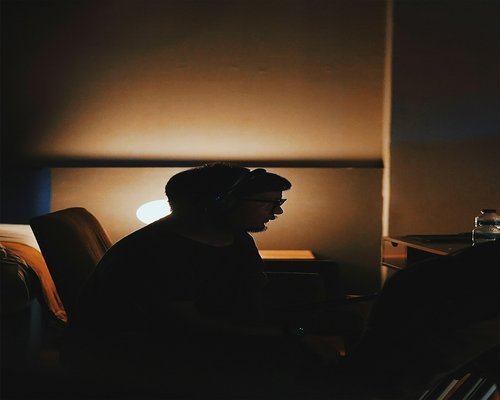 A person resting their eyes in a dimly lit, comfortable room
